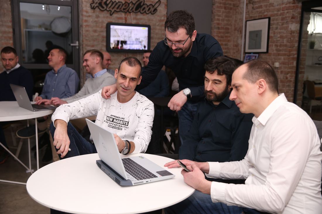 Team members huddled around a laptop during a working session