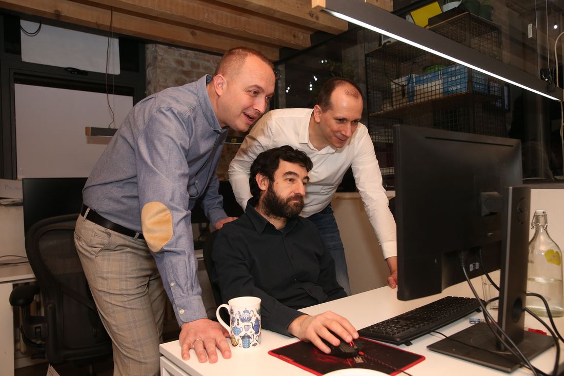 Two architects pairing with a developer at his desk